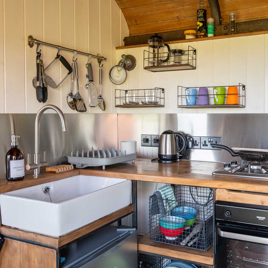 Fully equipped kitchen with a small fridge with freezer compartment, two burner hob, oven and prep space