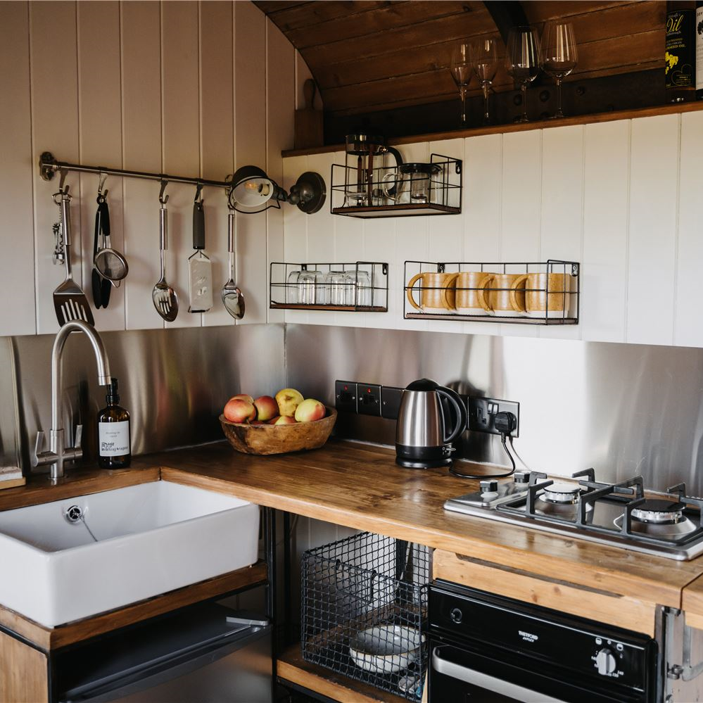 Fully equipped kitchen with a small fridge with freezer compartment, two burner hob, oven and prep space